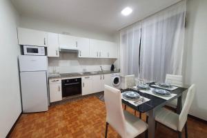 uma cozinha com mesa e cadeiras e uma cozinha com electrodomésticos brancos em Apartamento A Fontiña em Pontevedra