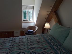 a bedroom with a bed and a chair and a window at The Old Cowshed in Roundwood