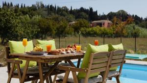 uma mesa de madeira com comida ao lado de uma piscina em Corfu Garden Villas em Corfu Town