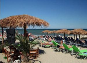 a group of people laying on the beach under umbrellas at AlenStudios in Paralia Katerinis