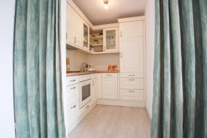 a kitchen with white cabinets and a blue shower curtain at Oland Whg 12 Lachmöwe in Wyk auf Föhr