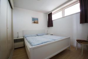 Un dormitorio blanco con una cama y dos ventanas. en Haus Uthlande Uthlande Whg 22 Seeluft, en Wyk auf Föhr 17 fotos más
