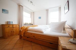 a bedroom with a bed with a wooden frame and two windows at Haus Uthlande Uthlande Whg 11 Strandglück in Wyk auf Föhr +24 photos
