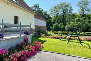 un jardín con un columpio en la hierba y flores en La Grange, en Moyenneville