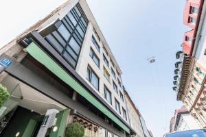 um edifício com acabamento verde e branco numa rua em Westend Hotel (non-smoking) em Munique