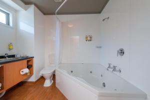 a white bathroom with a tub and a toilet at Beachcomber Inn Picton in Picton