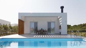 a villa with a swimming pool in front of a house at Corfu Garden Villas in Corfu