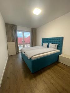a bedroom with a blue bed and a large window at Rekord Park Apartments in Cluj-Napoca