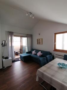 a living room with a blue couch and a table at Lily Apartments Punta Skala in Petrcane