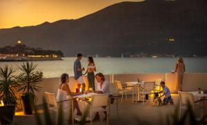 un gruppo di persone seduti ai tavoli su un balcone di Aminess Liburna Hotel a Korčula