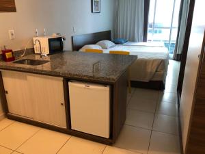 eine Küche mit einem Waschbecken und ein Schlafzimmer mit einem Bett in der Unterkunft Flat Beira-Mar Blue Sunset in João Pessoa