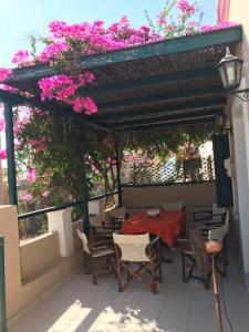 a table and chairs under a pergola with pink flowers at Villa Theoni in Halki