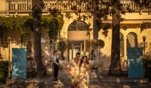 a bride and groom walking in front of a building at Aminess Younique Korcula Heritage Hotel in Korčula