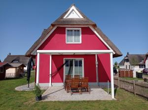 une maison rouge avec des chaises devant elle dans l'établissement Dat Papenboerger Hus, à Zierow