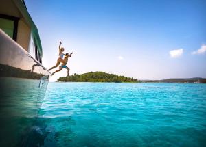 a person jumping off the side of a boat in the water at Aminess Younique Korcula Heritage Hotel in Korčula