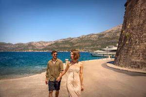 a man and a woman standing next to the water at Aminess Younique Korcula Heritage Hotel in Korčula