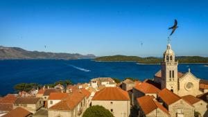 a bird flying over a town with a church at Aminess Younique Korcula Heritage Hotel in Korčula