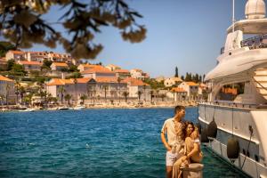 a man and a woman standing on a dock next to a boat at Aminess Younique Korcula Heritage Hotel in Korčula