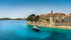 a boat in the water in front of a castle at Aminess Younique Korcula Heritage Hotel in Korčula