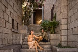 a woman and a man sitting on a stone wall at Aminess Korcula Heritage Hotel in Korčula