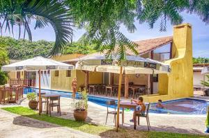 un complexe avec une piscine et des personnes assises à une table dans l'établissement APARTAMENTO 2 QUARTOS EQUIPADO NO BOSQUE DA PRAIA FLATS - PIPA NATUREZA, à Pipa