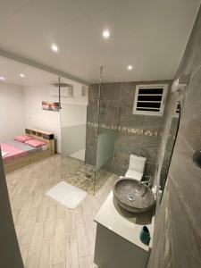 a bathroom with a sink and a shower and a bed at La Villa Navidad in Ducos