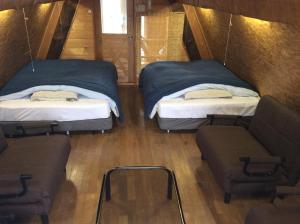 two beds and a chair in a small room at Woody Life in Kami-furano