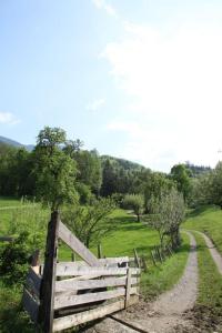 a wooden fence in a field with a dirt road at Jaklhof in Frasdorf