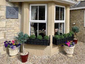 ein Haus mit drei Topfpflanzen und einem Fenster in der Unterkunft APSLEY VILLA GUEST HOUSE. in Cirencester