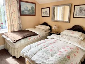 two twin beds in a room with a window at APSLEY VILLA GUEST HOUSE. in Cirencester