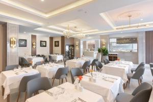 a restaurant with white tables and chairs and a chandelier at Hotel Riu Palace Maspalomas - Adults Only in Maspalomas