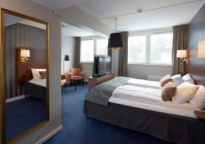 een hotelkamer met een groot bed en een spiegel bij Vänerport Stadshotell i Mariestad in Mariestad