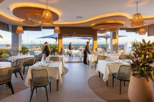 a restaurant with white tables and chairs and people in the background at Hotel Riu Palace Maspalomas - Adults Only in Maspalomas