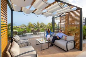 a man and woman sitting on a couch on a patio at Hotel Riu Palace Maspalomas - Adults Only in Maspalomas