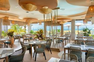 a restaurant with tables and chairs and windows at Hotel Riu Palace Maspalomas - Adults Only in Maspalomas