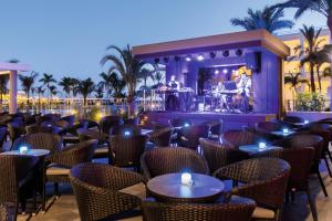 a bar with tables and chairs and a band on the stage at Hotel Riu Palace Maspalomas - Adults Only in Maspalomas