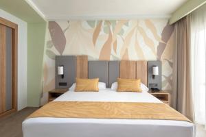 a bedroom with a large white bed with yellow pillows at Hotel Riu Palace Maspalomas - Adults Only in Maspalomas