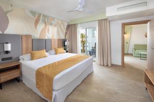 a bedroom with a large bed and a living room at Hotel Riu Palace Maspalomas - Adults Only in Maspalomas
