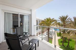 a balcony with chairs and a view of palm trees at Hotel Riu Palace Maspalomas - Adults Only in Maspalomas