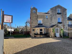 uma grande casa de pedra com um sinal em frente em APSLEY VILLA GUEST HOUSE. em Cirencester