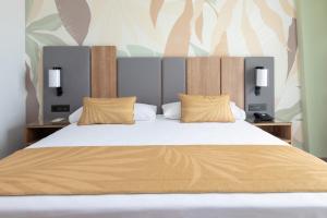 a bedroom with a large bed with two night stands at Hotel Riu Palace Maspalomas - Adults Only in Maspalomas