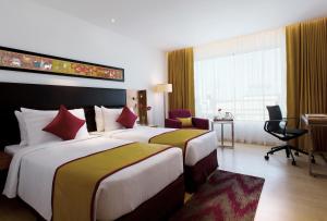 a hotel room with two beds and a desk at Mercure Hyderabad KCP Banjara Hills, An Accor Hotel in Hyderabad