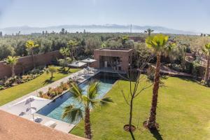 an aerial view of a villa with a swimming pool and palm trees at Villa familiale aux portes de Marrakech in Marrakesh