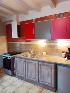 a kitchen with red cabinets and a sink and a stove at DUPLEX "Au Village" 89120 Dicy in Dicy