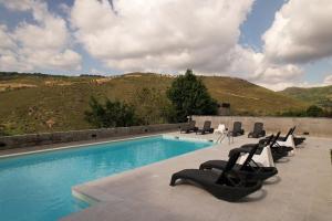 a swimming pool with lounge chairs and a mountain at Quinta dos Castanheiros - Turismo Rural in Negreda