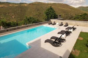 a swimming pool with lounge chairs next to a mountain at Quinta dos Castanheiros - Turismo Rural in Negreda