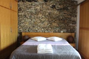 a bedroom with a bed with two pillows and a stone wall at Quinta dos Castanheiros - Turismo Rural in Negreda +37 photos