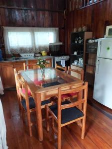 cocina con mesa de madera con sillas y nevera blanca en Colinas de Mindo, en Mindo