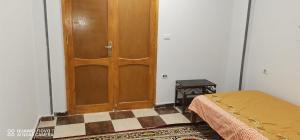 a bedroom with a wooden door and a checkered floor at Tut flat in Luxor +9 photos