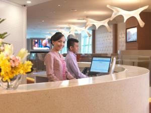 a man and a woman standing at a counter with a laptop at Sama-Sama Express KLIA Terminal 2 - Airside Transit Hotel in Sepang